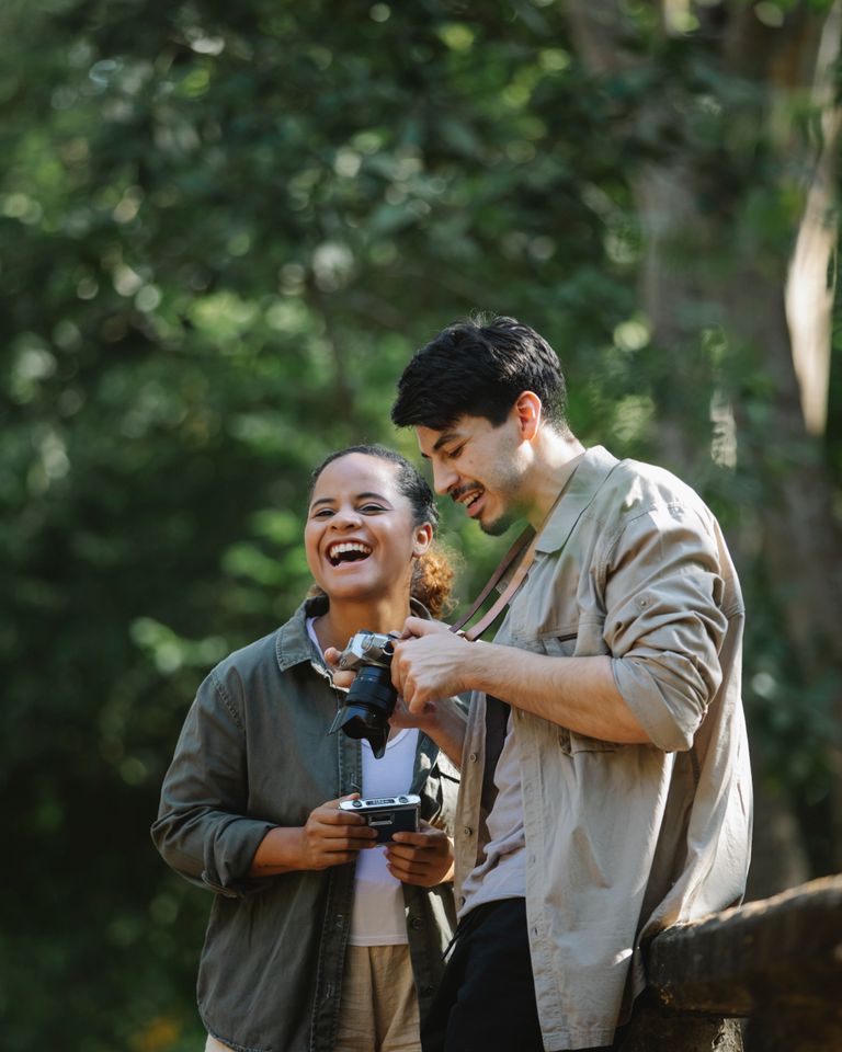 A couple laughing outdoors while taking photos together